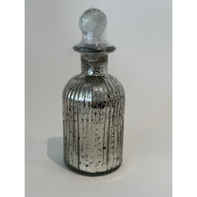 Set of three decorative mercury glass decorative bottles with faceted stoppers. The largest one has a ribbed design and it...
