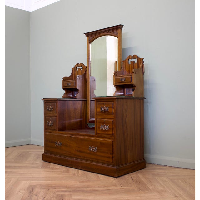 A mahogany dressing chest, circa 1900, with a tall bevelled mirror, carved detailing and decorative brass handles. Seven...