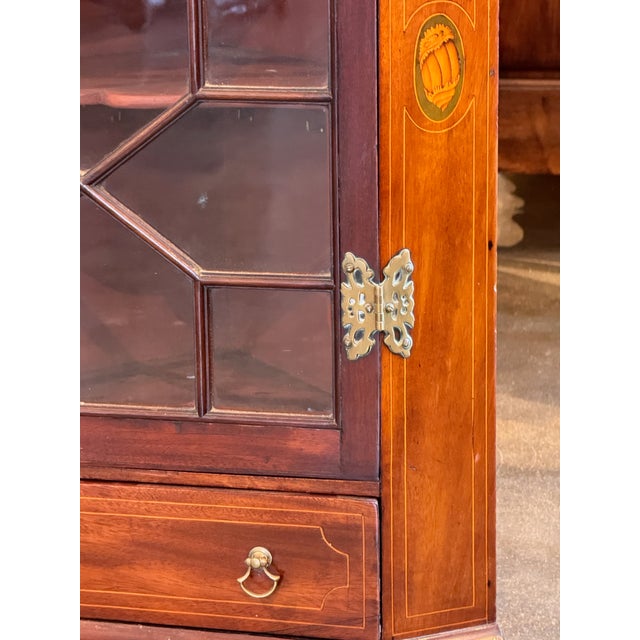Wall-mounted corner cupboard with dentil-molded cornice above a single glazed door with geometric muntin pattern. Door...