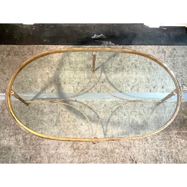 A vintage Minton-Spidell oval coffee table with a thick glass top with a half-inch bevel, heavy gilded neoclassical style...