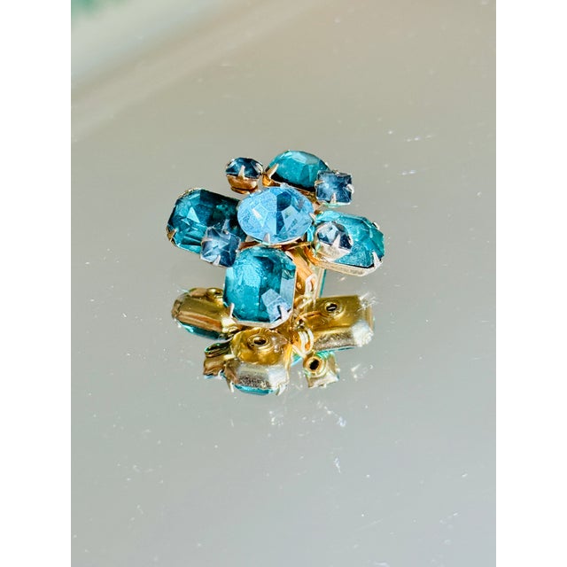1960s dimensional Maltese cross brooch featuring a highly raised, multi tiered cluster of emerald green, teal, aqua, and...