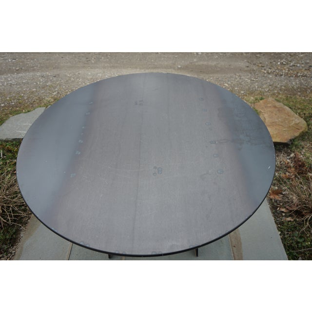 This round industrial-style table features a dark gray steel top with a protective finish, a minimalistic foldable base,...