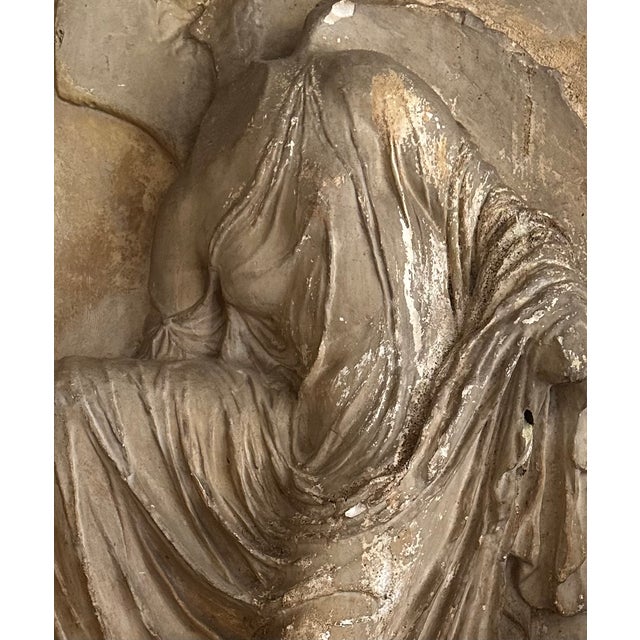 A beautiful large-scale antique plaster relief depicting Nike, the Greek goddess of victory, adjusting her sandal....