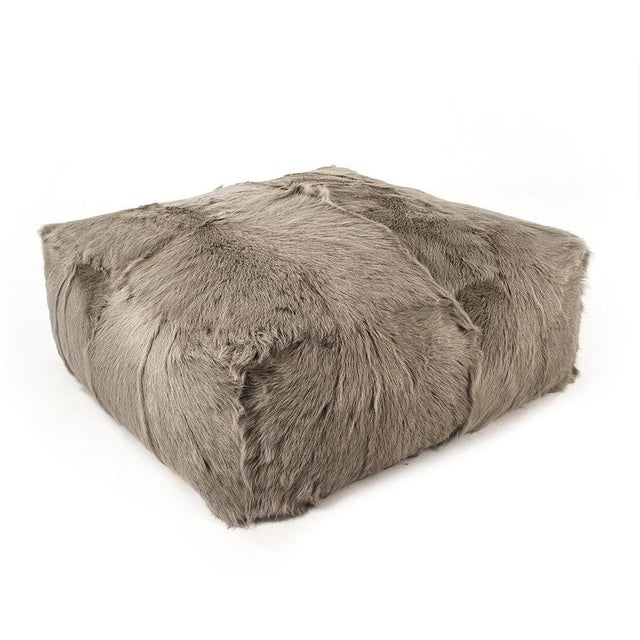 The Tibetan Goat Fur Ottoman from Zentique is a large round ottoman with a removable light grey Tibetan goat fur cover on...