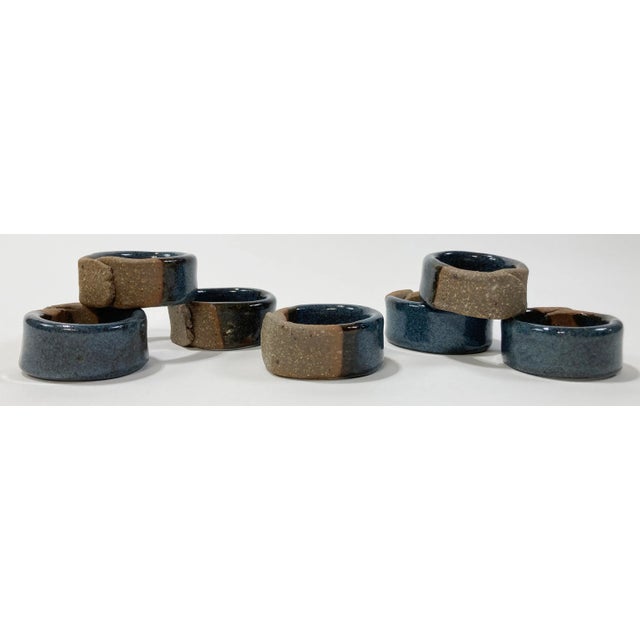 Unique set of 7 handcrafted stoneware napkin rings. Half the ring is unglazed and overlaps to connect while the other half...