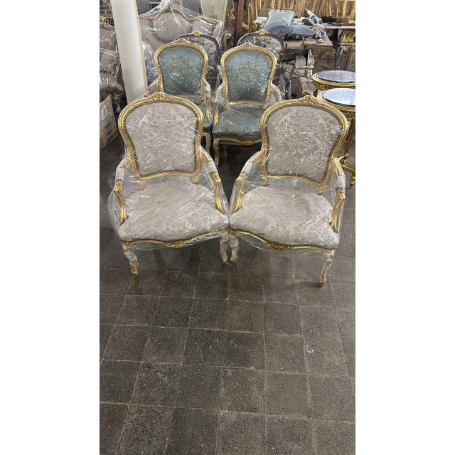An elegant French Louis XV-style armchairs, beautifully combining an ornate gold-finished carved wood frame with...