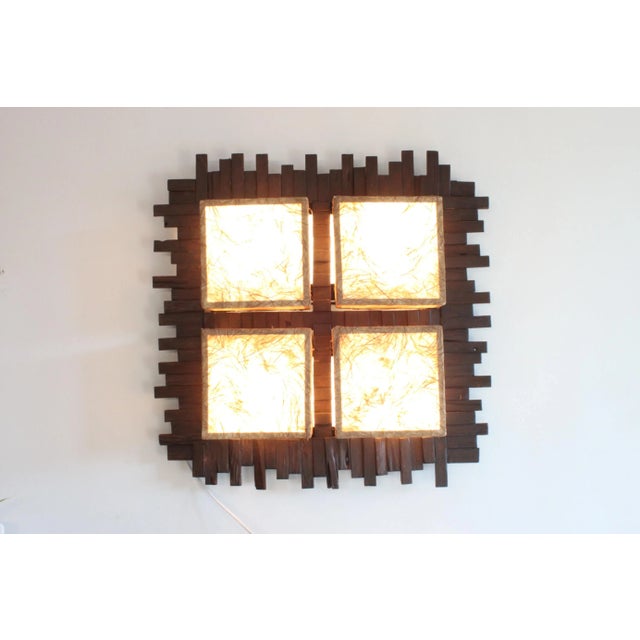 A scandinavian modern or tropical style wall lamp made off little pieces of wood with four lights in a fabric frame....