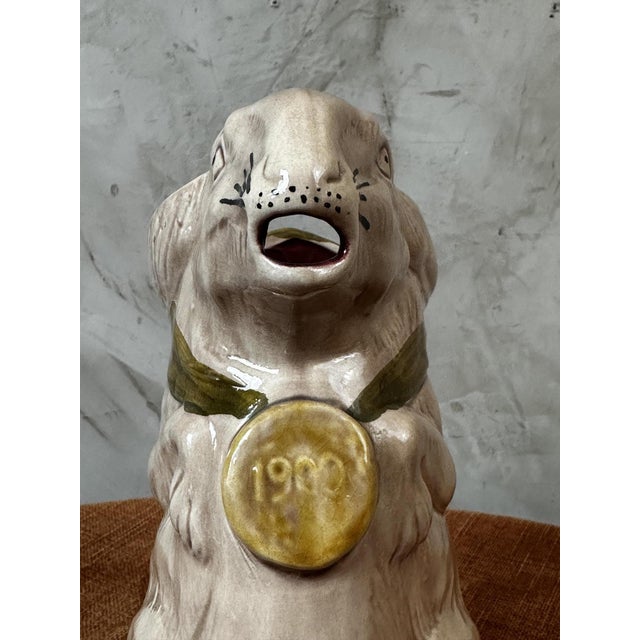 A rare earthenware pitcher dating from the 1900s, depicting a rabbit wearing an elegant green scarf. Its expressive...