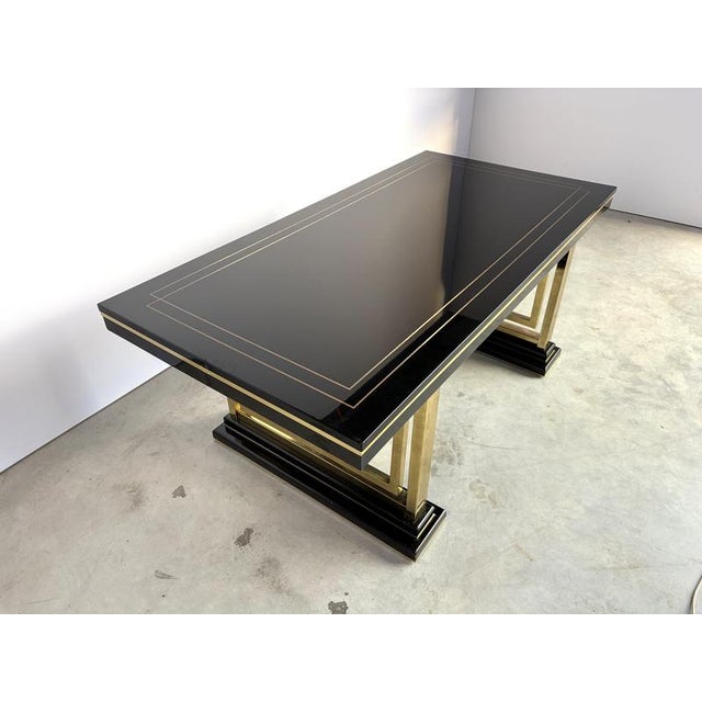 Vintage seventies glam dining table made from black lacquered wood and brass. The black lacquer with golden finish gives a...