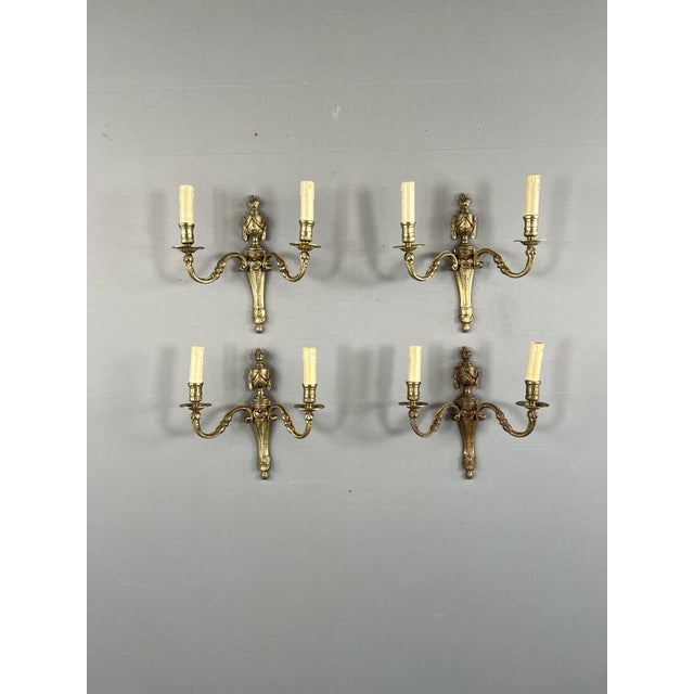 An elegant set of four bronze wall sconces in the Louis XVI style. Each sconce features two delicately curved arms adorned...