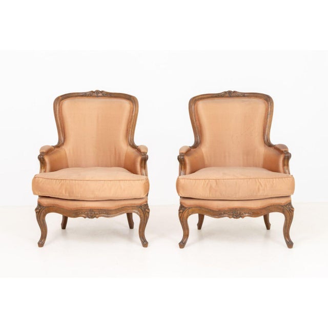Pair of Louis XV Satin Upholstered Walnut Bergeres, with carved floral motif crests, stamped for Nicolas-Quinibert Foliot...
