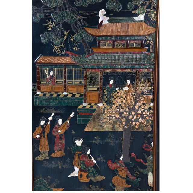 This captivating framed Asian panel showcases a masterful enamel and stone inlay on wood, depicting a serene outdoor scene...
