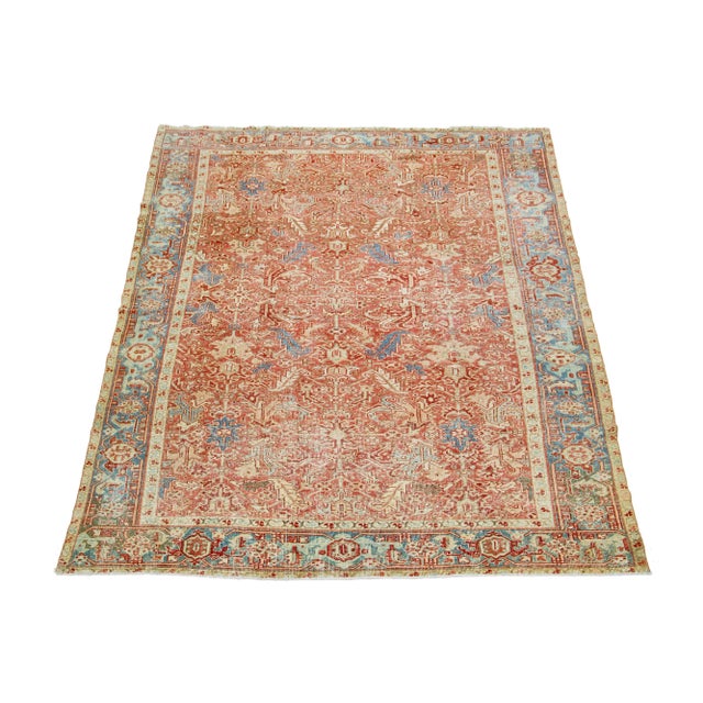 The antique Heriz rug displays its impressive medallion design and hand-knotted wool construction. The soft rust field is...