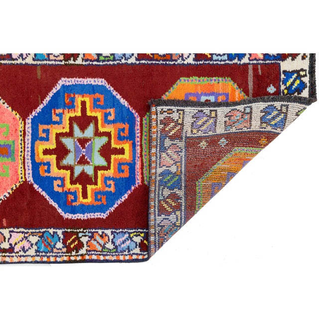 Handwoven in Turkey, this vibrant runner features a series of bold octagonal medallions set against a rich red field....