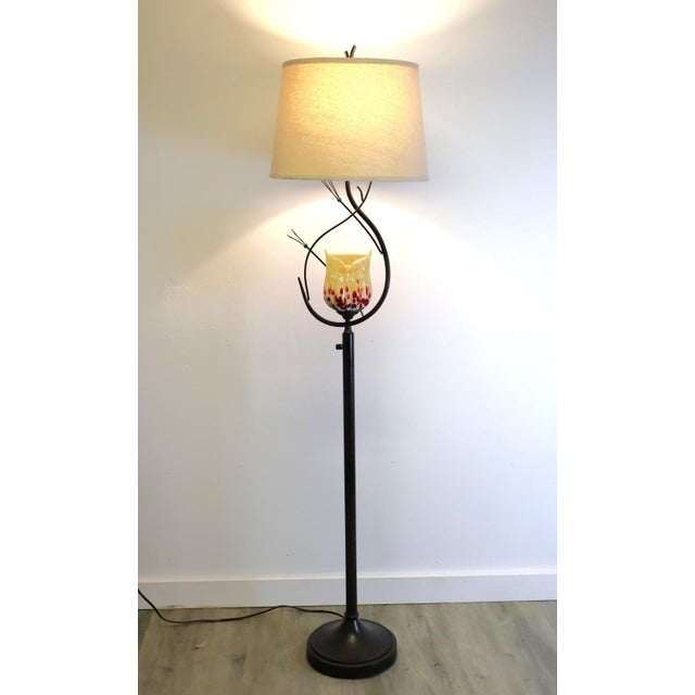 A Dale Tiffany Spotted Owl floor lamp featuring a beautifully hand-crafted amber art glass owl nestled within sculptural...