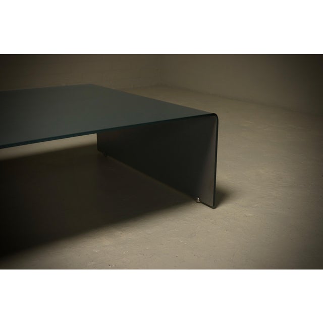 Italian modern coffee table from the 1980s. The table is made from a single sheet of thick bent glass with a classic...