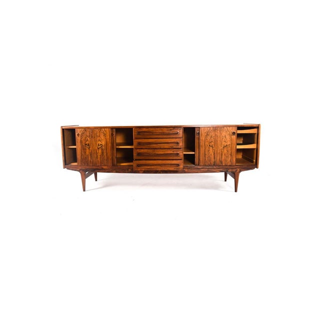 Danish rosewood sideboard. The cabinet has four drawers in center and sliding doors on either side. Oak interior with...