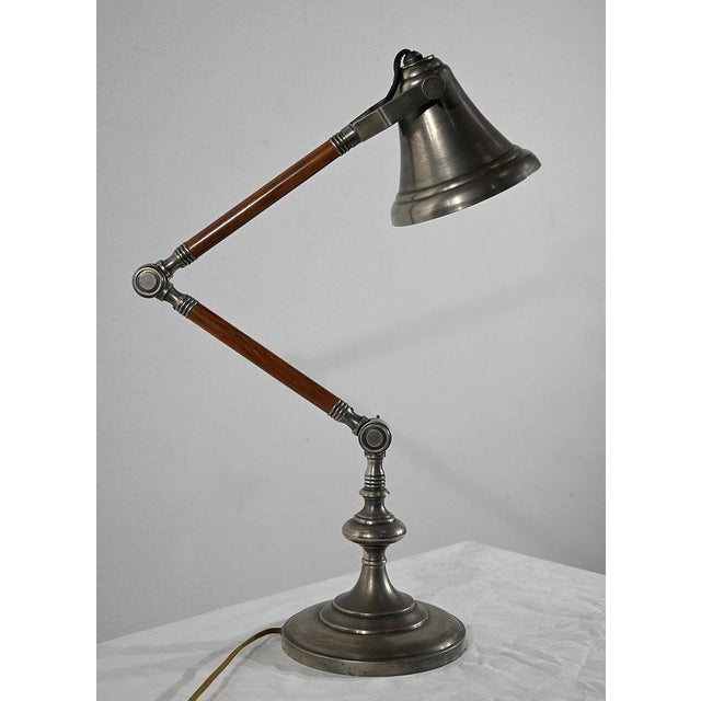 This lamp has a metal lampshade, in the shape of a bell, adjustable using side knobs. This is fixed on an articulated arm...