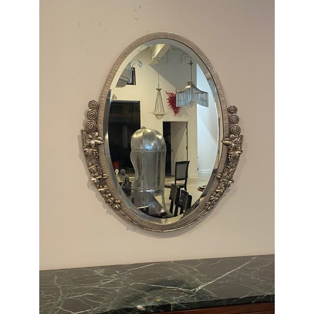 French Art Deco oval mirror with floral and geometric motifs. The frame has been re plated in a polished nickel. The...