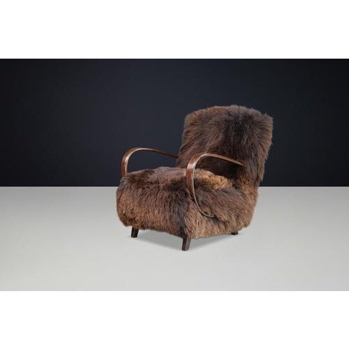 An iconic 1940s halabala lounge chair, newly upholstered in rich dutch sheepskin, combining sculptural bentwood...