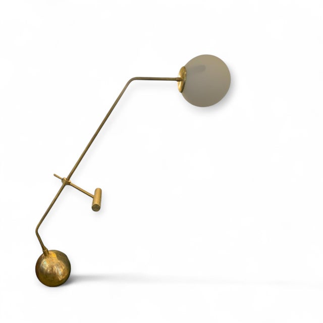 This contemporary table lamp is crafted from gold-plated metal with a spherical base for added stability. Its articulated...