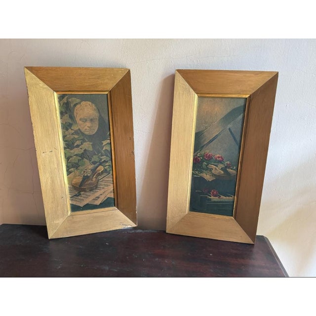 Pair of vintage-style still life artworks featuring violin and floral arrangements in traditional interiors. One...