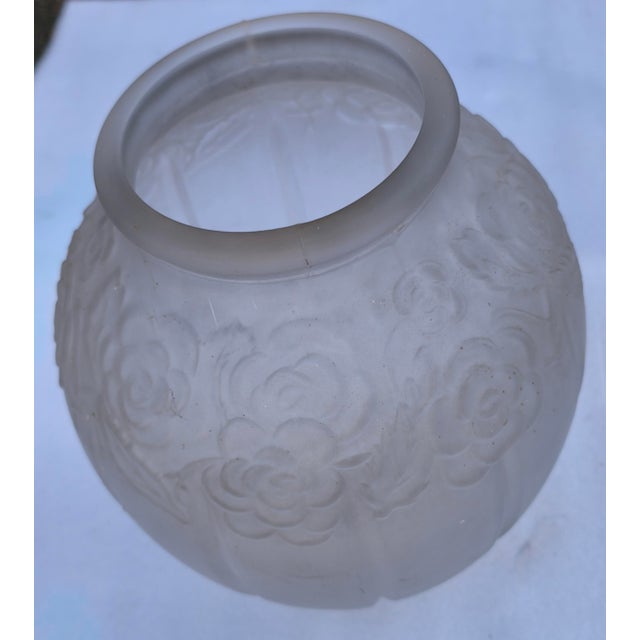 The vase pictured is a satin-finished Art Deco spherical vase made of pressed glass with a raised floral or rose pattern,...