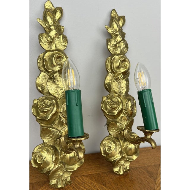 A beautiful pair of vintage French sconces featuring an elegant floral rose design with richly detailed gold tone finish....