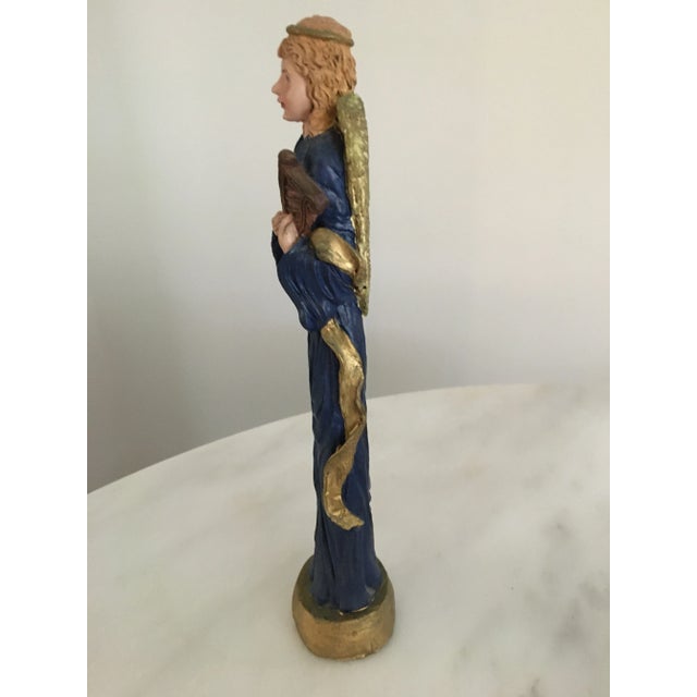 A sweet disproportionately tall hand painted chalkware angel. Holding a small harp, she has on a deep blue robe with a...