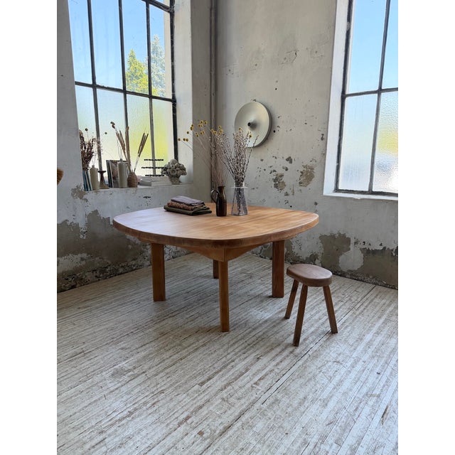 An antique dining table with a constructivist style, featuring a large, rounded top resting on a simple base with...