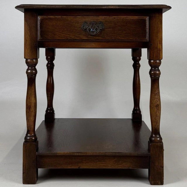 A charming early 20th-century English side table, finely crafted from oak and distinguished by its traditional turned...
