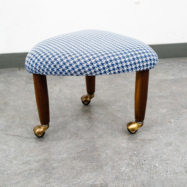 Rolling guitar pick shaped ottoman in white and blue upholstery. Solid wood legs.