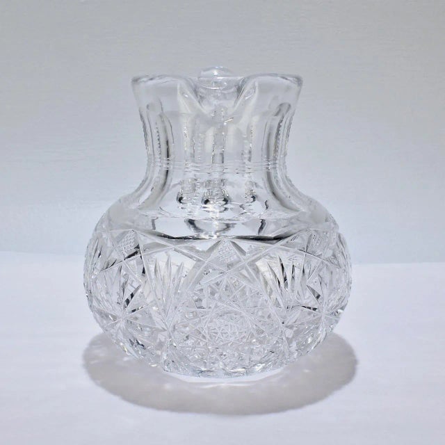 A fine antique small-scale cut glass juice or cocktail pitcher. The body of the pitcher is bulbous or squat (like a...
