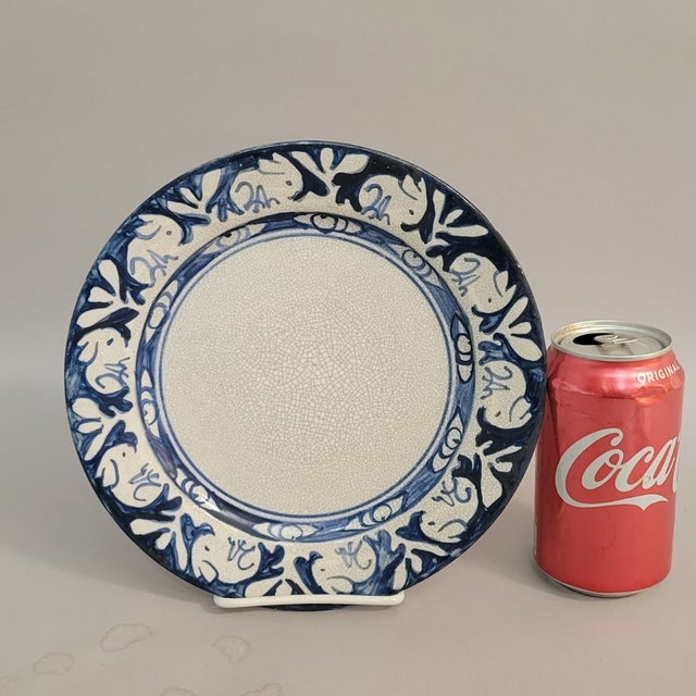 A charming Dedham Pottery plate featuring a repeating rabbit motif in rich cobalt blue on the studio’s signature crackle-...