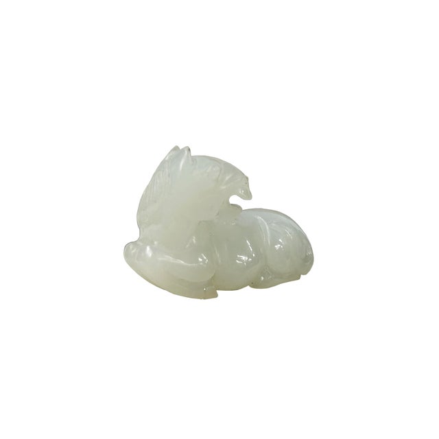 This exquisitely carved white stone pendant depicts a recumbent horse in a restful, folded pose, showcasing smooth,...