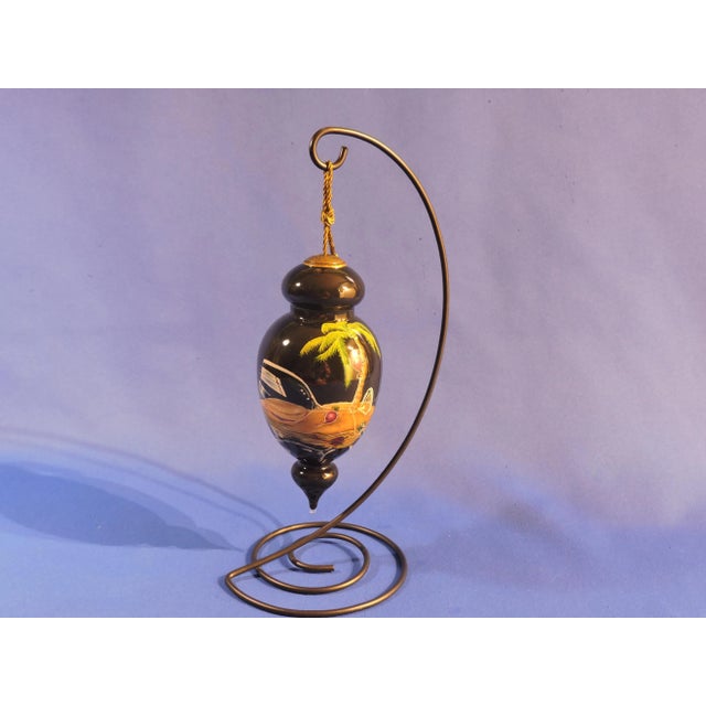 This hand blown reverse hand painted glass ornament was made by the artist Michael Godard who named this piece Lost In...