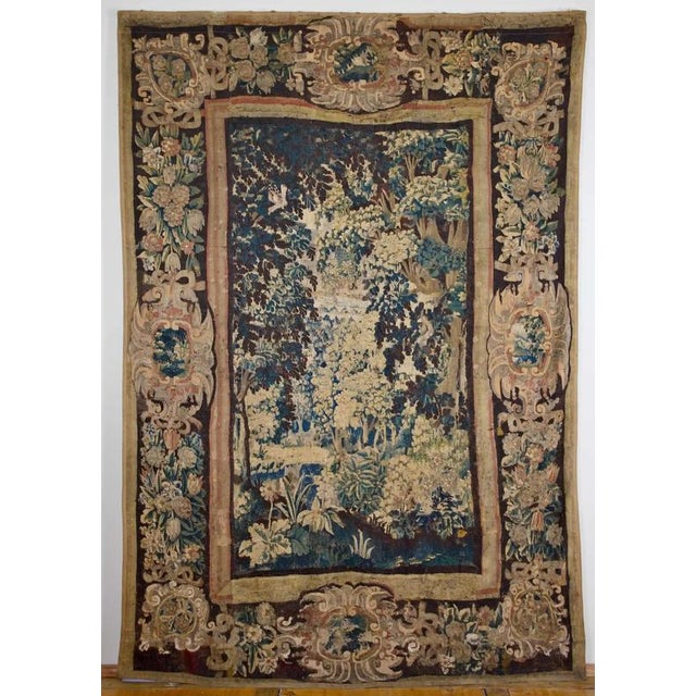 The large hand-woven tapestry depicts a forest landscape, the deep vista of which is opened by massive trees with densely...