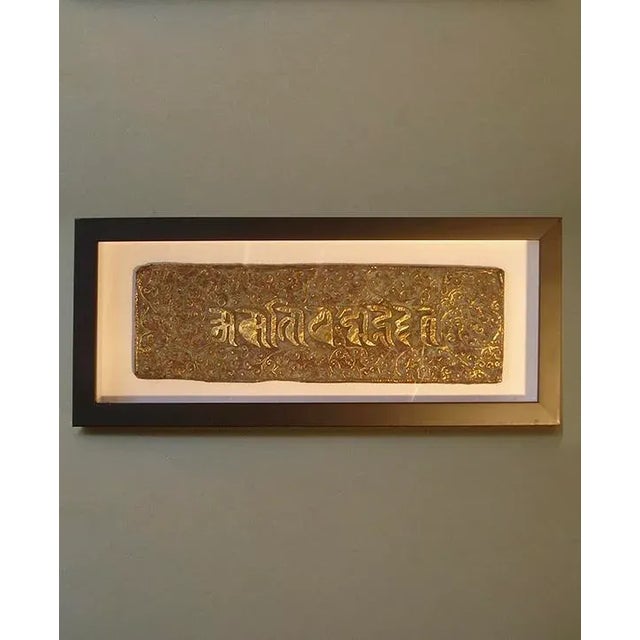 framed in a covered shadow box, the book cover is made of wood that is wrapped in a repousse sheet of bronze, decorated...