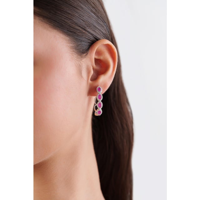 These contemporary hoop earrings showcase 2.02 carats of natural oval rubies, set in 14K white gold. Each ruby measuring...