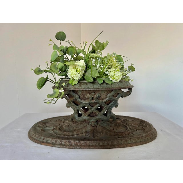 A rare early ornate cast iron planter urn raised with a woven iron support. It has the original paint with enamel on the...