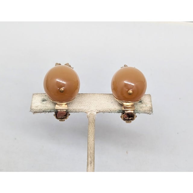 1950s goldtone ellipsoid tan "peach" moonglow with goldtone top pineapple clip earrings. Marked "NAPIER PAT. PEND." on the...