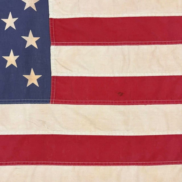 This vintage American flag is made from a cotton cloth with fully sewn stripes and 50 printed stars. Please note staining...