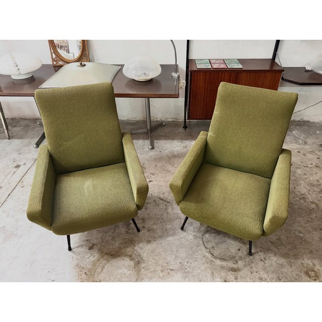 A pair of 1950s italian armchairs, with a wooden frame, black lacquered metal legs, and original green bouclé fabric...