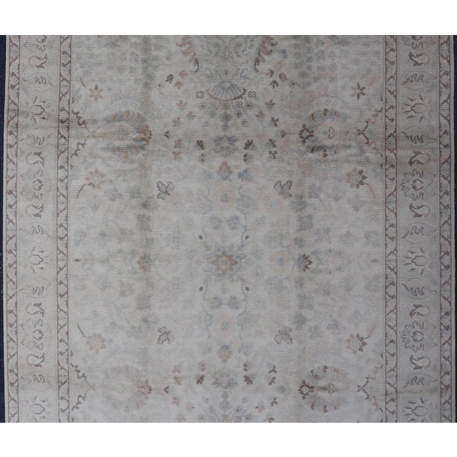 Measures: 6'0 x 9'9 Produced in mid-20th century Turkey, this vintage Oushak is characterized by a comely and highly...