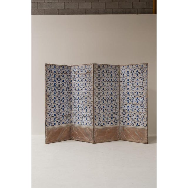 A remarkable 19th-century Italian folding screen featuring four panels decorated with hand-painted blue ornamental motifs...