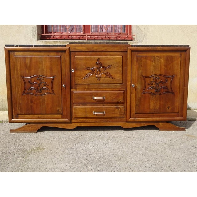 Large solid walnut sideboard with straight, rectilinear curves. Three solid wood cupboard doors with a central motif and...