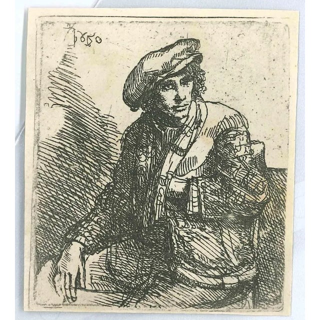 Zittende jongeman met een tas is an etching on ivory-colored paper realized after an etching by Rembrandt dated 1650. This...