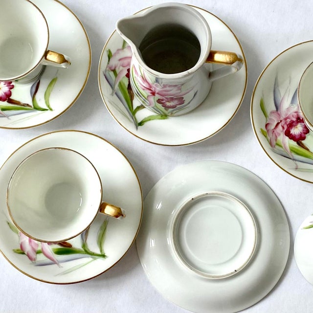 Charming set of four vintage demitasse cups & saucers with matching creamer are hand-painted with pink flowers and...