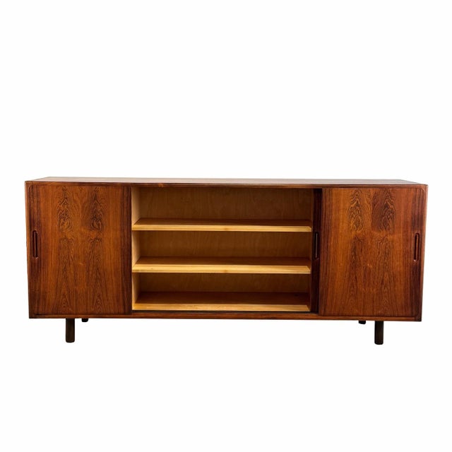 An impressive statement piece, this vintage rosewood sideboard features beautiful lines with four sliding doors, sleek...