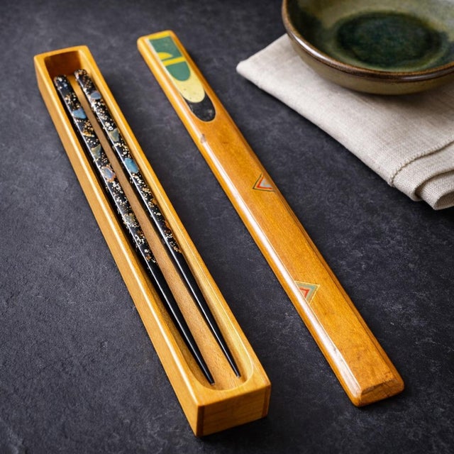 A refined vintage Japanese chopstick set featuring black lacquer chopsticks with genuine mother-of-pearl inlay and gold...